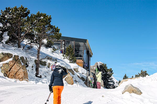 Photo d'une skieuse qui va vers un restaurant d'altitude avec ses skis.